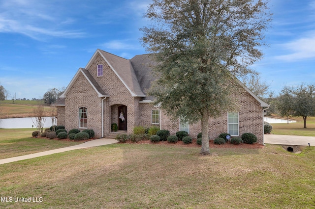 view of front facade featuring a front lawn, a water view, and brick siding