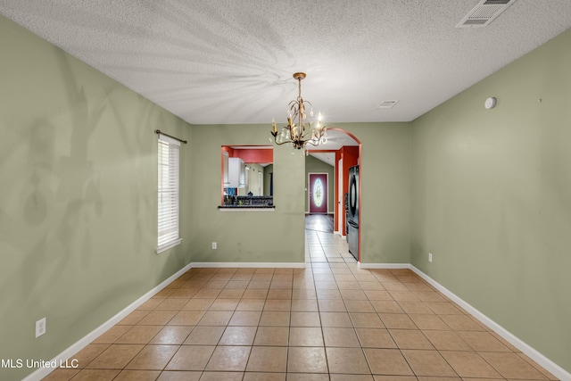 3005 Robalo Dr, Gautier, MS 39553 - spare room featuring arched walkways, light tile patterned flooring, a chandelier, and a textured ceiling