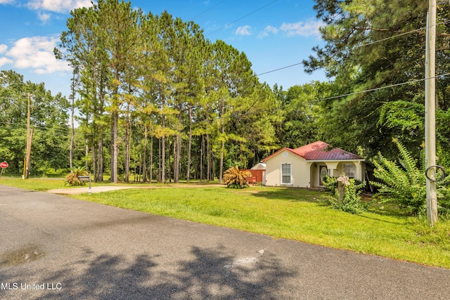 3005 Robalo Dr, Gautier, MS 39553 - view of front of home with stucco siding, a front yard, and a forest view