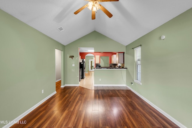 3005 Robalo Dr, Gautier, MS 39553 - unfurnished living room with arched walkways, a ceiling fan, vaulted ceiling, and wood finished floors