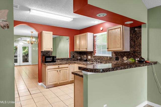 3005 Robalo Dr, Gautier, MS 39553 - kitchen featuring black microwave, a textured ceiling, light brown cabinets, a peninsula, and plenty of natural light