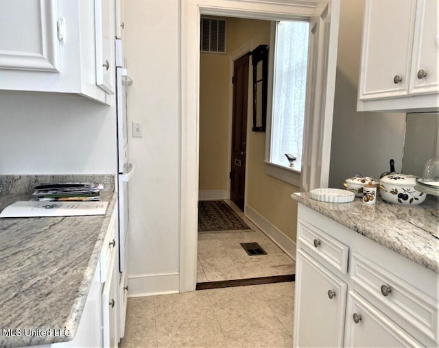 707 State St Unit 705, Natchez, MS 39120 - kitchen with white cabinetry, baseboards, light tile patterned flooring, and light stone counters