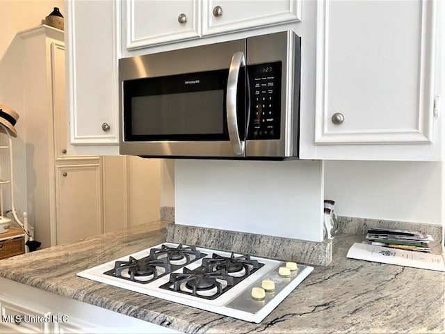 707 State St Unit 705, Natchez, MS 39120 - kitchen with stainless steel microwave, white gas stovetop, white cabinets, and light stone counters