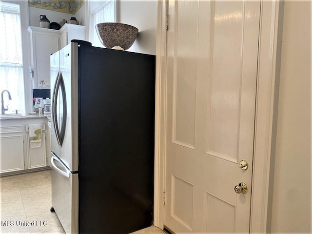 707 State St Unit 705, Natchez, MS 39120 - kitchen with freestanding refrigerator, a sink, white cabinets, light tile patterned floors, and light countertops