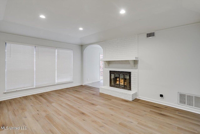 unfurnished living room with a brick fireplace and light wood-type flooring