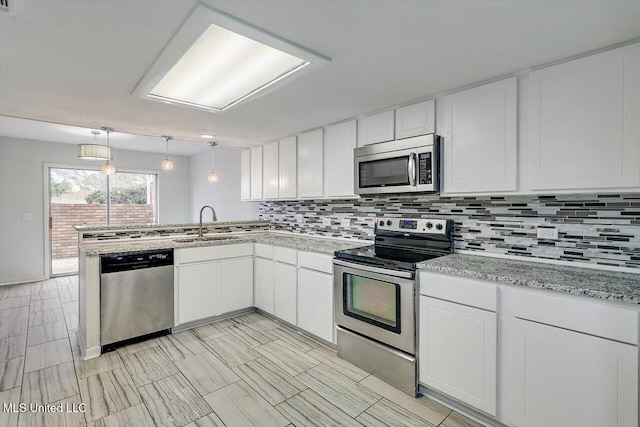 kitchen with stainless steel appliances, decorative backsplash, white cabinets, and decorative light fixtures