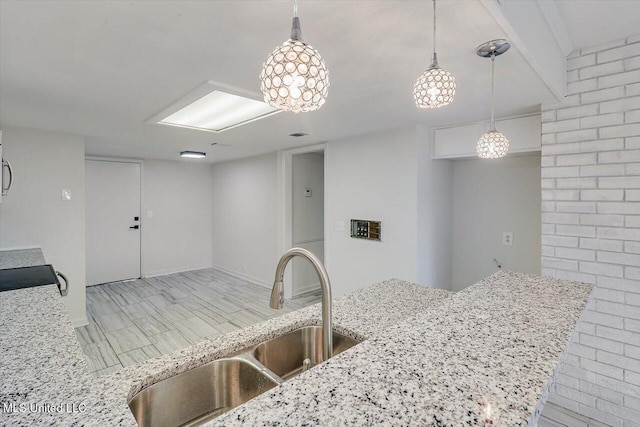 kitchen featuring light stone counters, sink, decorative light fixtures, and range