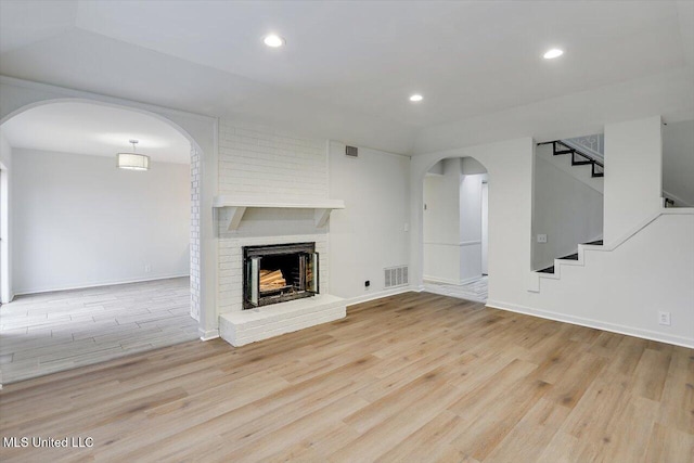 unfurnished living room with a brick fireplace and light wood-type flooring