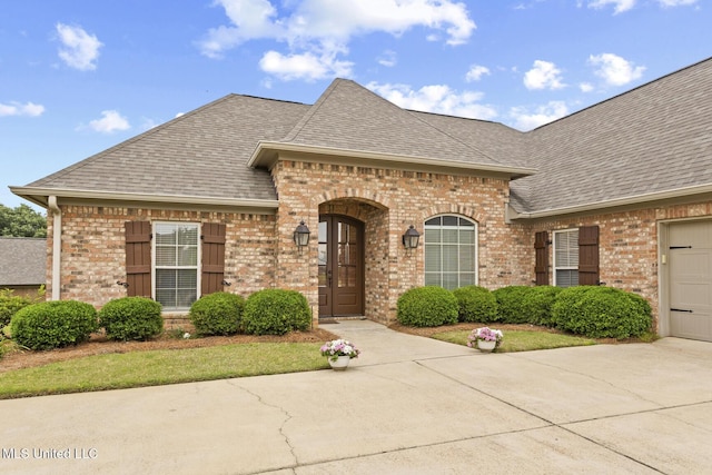 130 Camden Xing, Madison, MS 39110 - french country style house featuring brick siding, roof with shingles, concrete driveway, and a garage