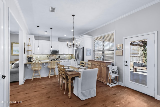 dining area with ornamental molding, dark hardwood / wood-style floors, and a chandelier