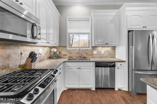 kitchen featuring sink, crown molding, appliances with stainless steel finishes, light stone countertops, and white cabinets