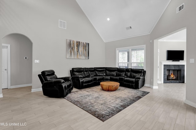 living room featuring crown molding, a fireplace, and high vaulted ceiling