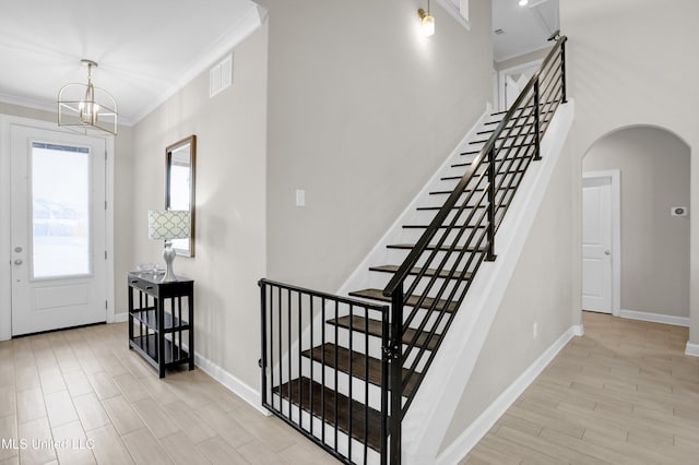 entryway with an inviting chandelier, ornamental molding, and light hardwood / wood-style floors