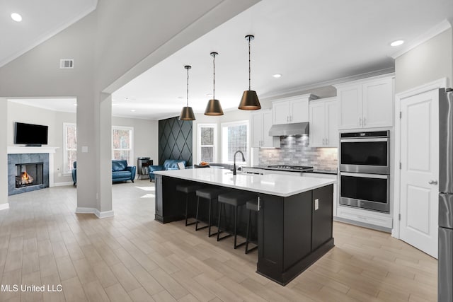 kitchen featuring sink, an island with sink, stainless steel appliances, and white cabinetry