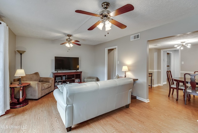 living area with light wood-type flooring, ceiling fan, and baseboards