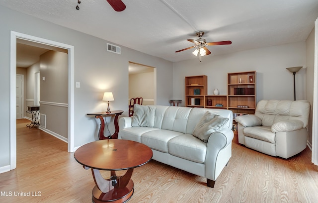 living room featuring a ceiling fan, light wood-type flooring, and baseboards