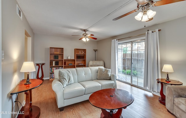living area with a ceiling fan, wood finished floors, and baseboards