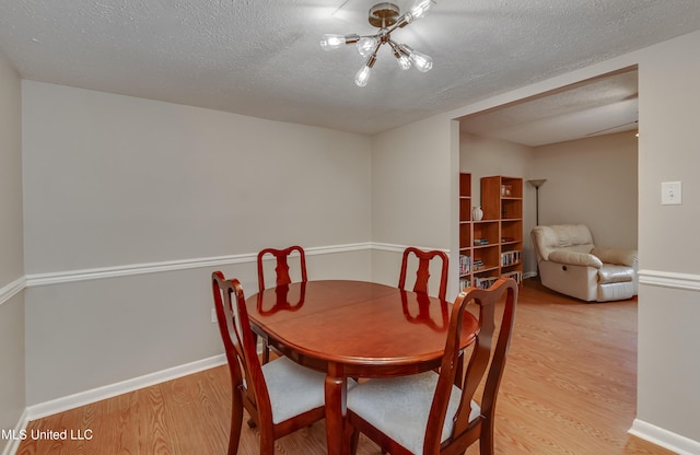 dining room featuring light wood finished floors, a textured ceiling, and baseboards