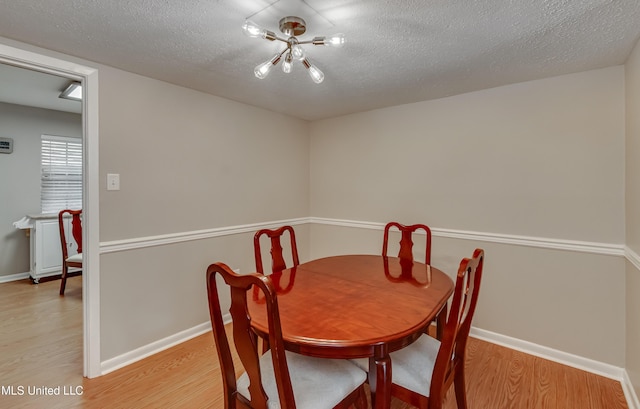 dining area with light wood-style floors, a textured ceiling, and baseboards