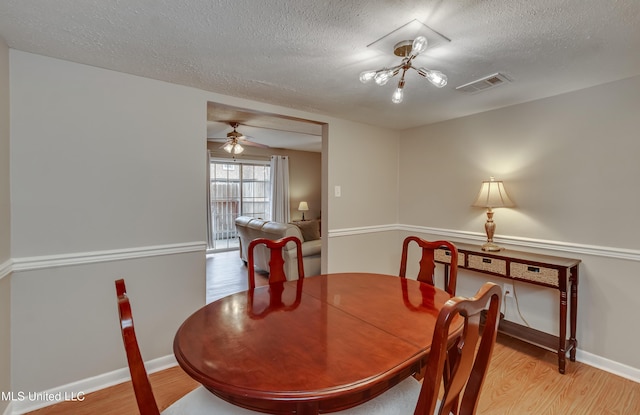 dining room with wood finished floors, a textured ceiling, baseboards, and a ceiling fan