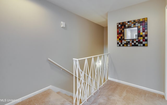 hallway with an upstairs landing, baseboards, and carpet