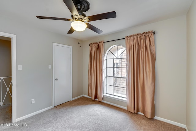 unfurnished room with carpet floors, a ceiling fan, plenty of natural light, and baseboards