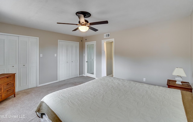 carpeted bedroom featuring two closets, ceiling fan, and baseboards