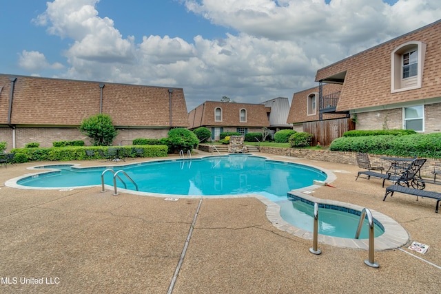 community pool with a patio area and fence