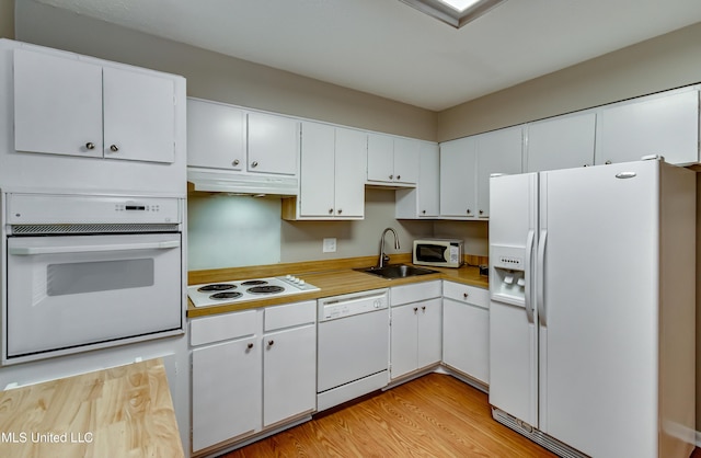 kitchen featuring white appliances, a sink, under cabinet range hood, light countertops, and white cabinets