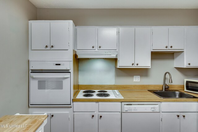 kitchen featuring white appliances, a sink, under cabinet range hood, light countertops, and white cabinetry