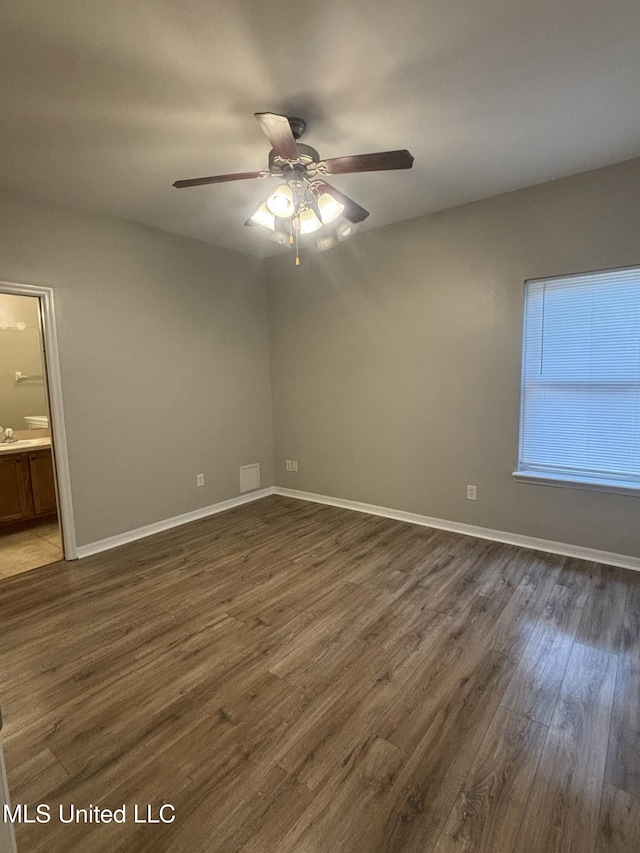 empty room with ceiling fan, baseboards, and dark wood finished floors