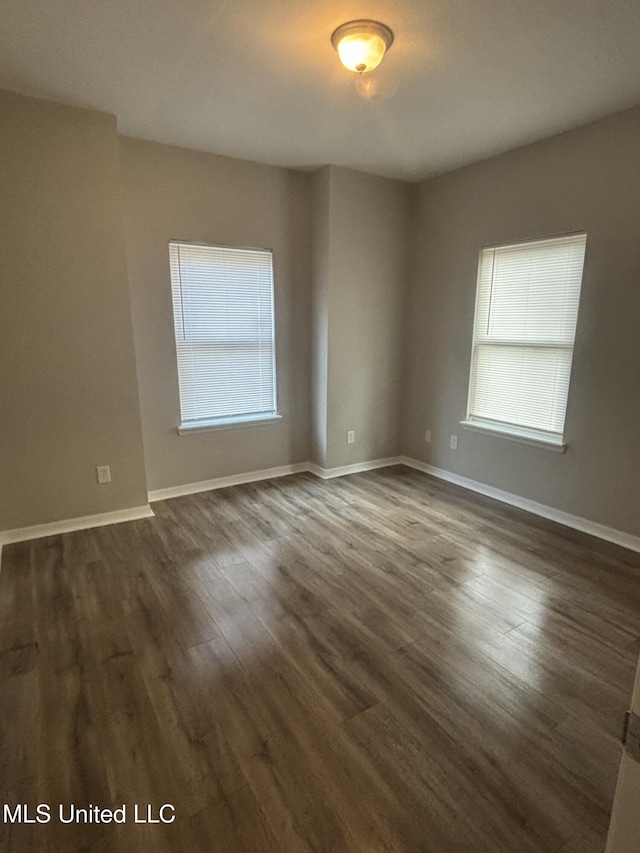 empty room with baseboards and dark wood finished floors