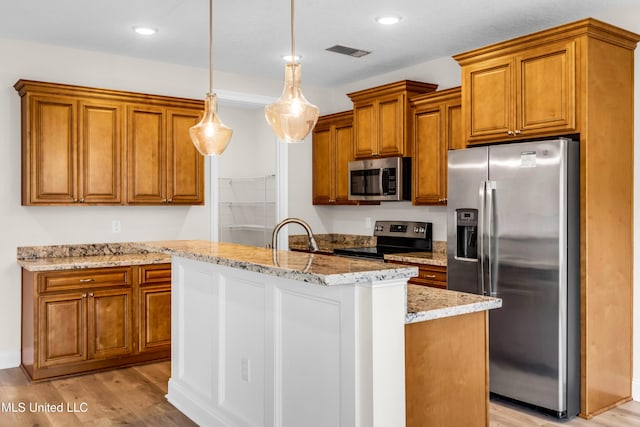 14864 Audubon Lake Blvd, Gulfport, MS 39503 - kitchen featuring stainless steel appliances, brown cabinets, light wood-style flooring, a center island with sink, and recessed lighting