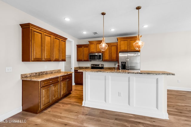 14864 Audubon Lake Blvd, Gulfport, MS 39503 - kitchen with stainless steel appliances, brown cabinets, light stone counters, light wood-style floors, and decorative light fixtures