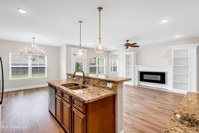 14864 Audubon Lake Blvd, Gulfport, MS 39503 - kitchen with stainless steel dishwasher, brown cabinets, light wood-type flooring, a glass covered fireplace, and recessed lighting