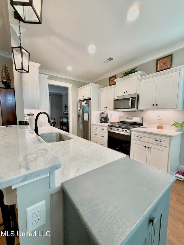 kitchen with sink, appliances with stainless steel finishes, white cabinetry, ornamental molding, and kitchen peninsula