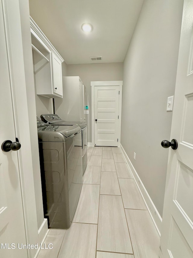 clothes washing area with cabinets and independent washer and dryer