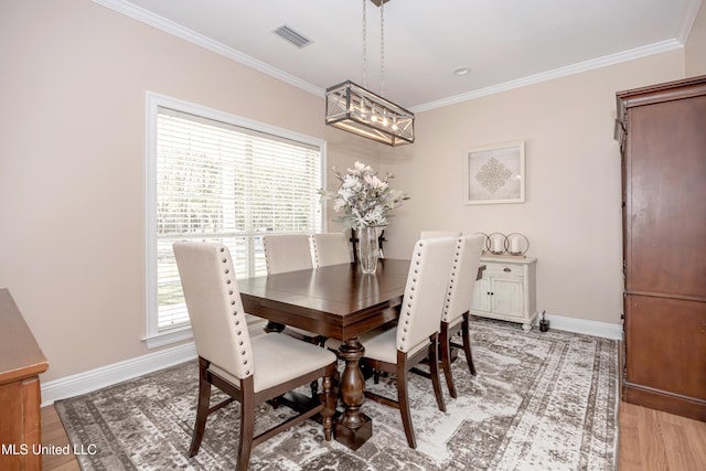 dining area with ornamental molding and light wood-type flooring