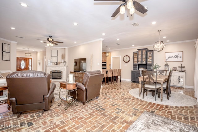 living room with ornamental molding and ceiling fan with notable chandelier