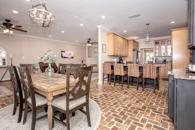 dining area featuring ceiling fan with notable chandelier and crown molding