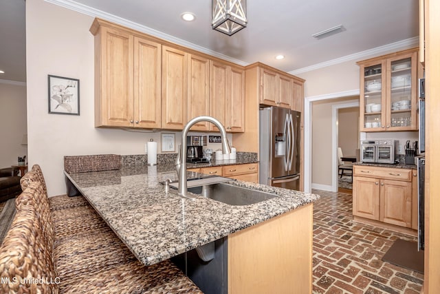 kitchen with light brown cabinetry, stainless steel fridge with ice dispenser, crown molding, stone counters, and sink