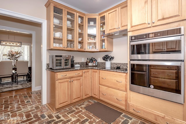 kitchen with dark stone counters, a notable chandelier, black electric cooktop, light brown cabinetry, and stainless steel double oven