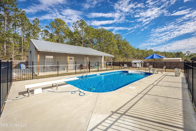 view of swimming pool featuring a patio area and a diving board