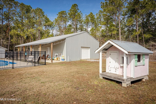 view of outdoor structure with a garage, a yard, and a fenced in pool