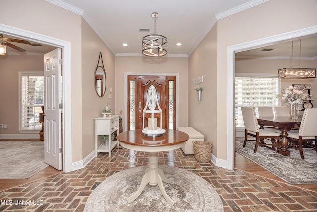 entrance foyer with a healthy amount of sunlight, crown molding, and ceiling fan with notable chandelier