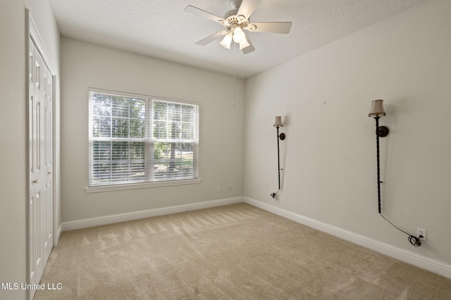 carpeted spare room featuring a textured ceiling and ceiling fan