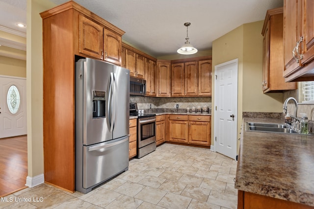 kitchen with appliances with stainless steel finishes, sink, light hardwood / wood-style floors, decorative light fixtures, and crown molding