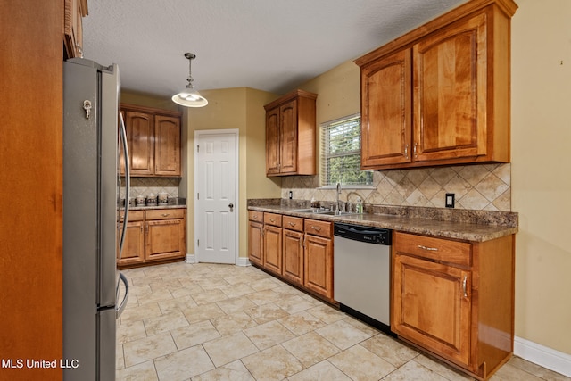 kitchen featuring tasteful backsplash, a textured ceiling, stainless steel appliances, sink, and decorative light fixtures