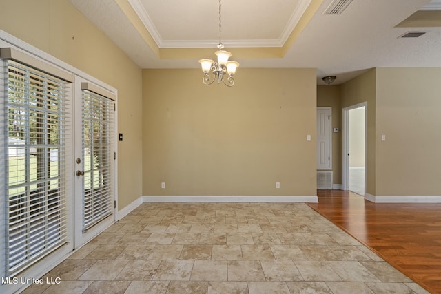 empty room featuring light hardwood / wood-style flooring, ornamental molding, a chandelier, and a tray ceiling