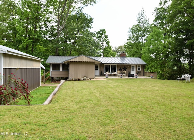 back of house with a lawn, a chimney, and metal roof
